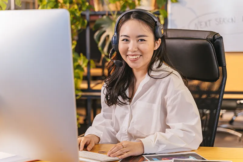 An office coordinator taking a call on a headset at a desk